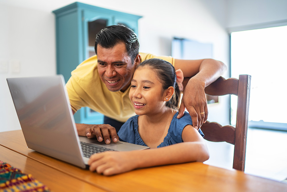 father helping daughter on laptop