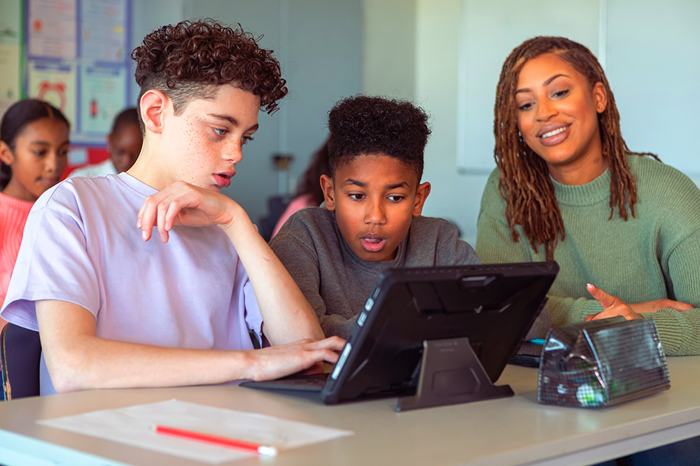Two male students receiving assistance from teacher
